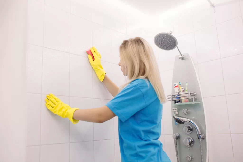 Cleaning lady cleaning shower tiles